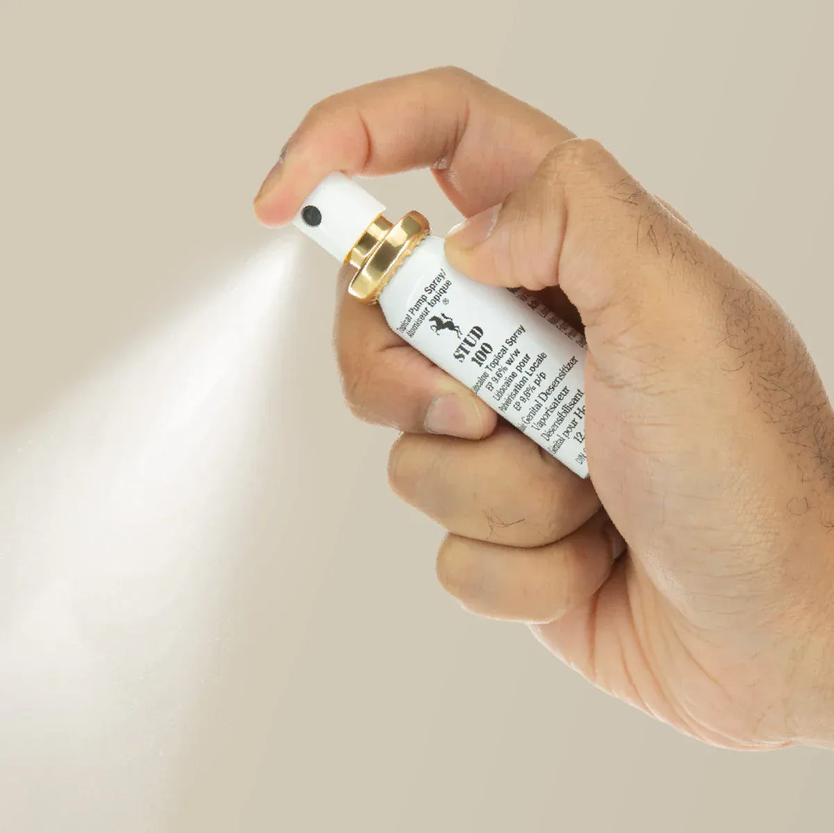 Hand holding a male desensitizer spray bottle with a beige background